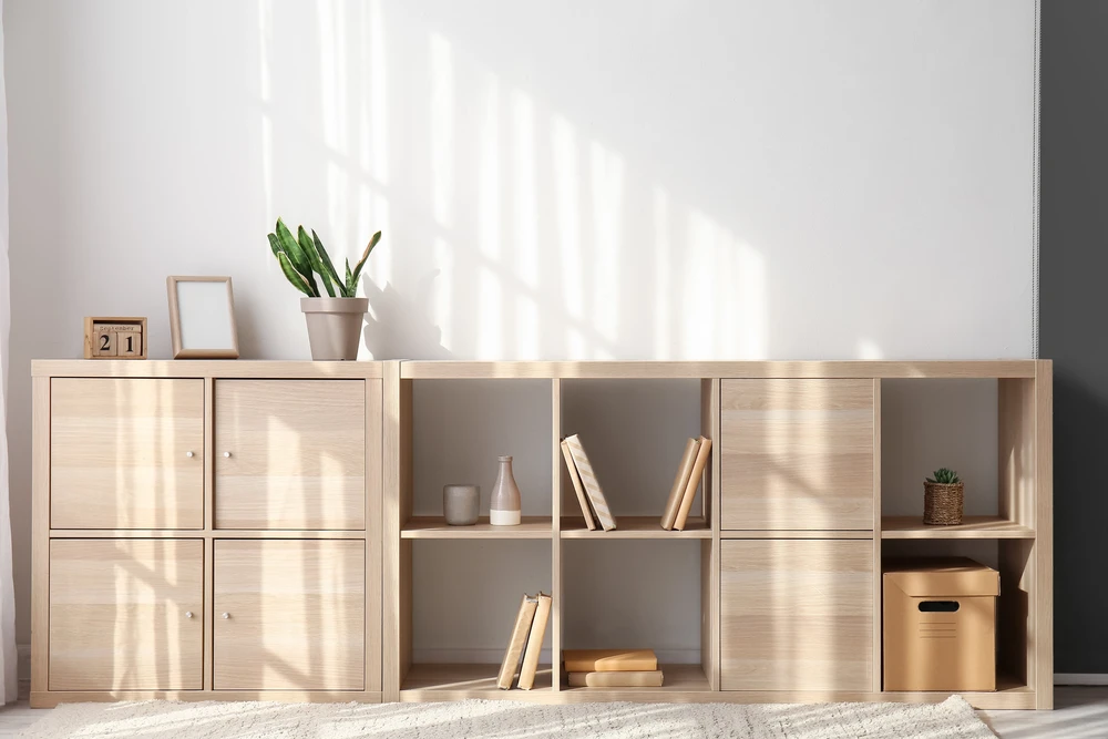 Intérieur moderne minimaliste avec meuble TV blanc, télévision murale noire, enceinte colonne haute-fidélité et orchidée blanche en pot