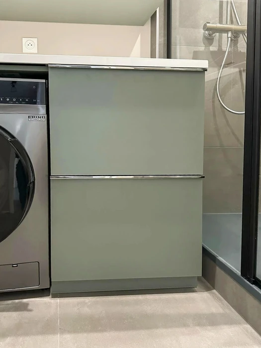 Salle de bain moderne avec meuble bas à deux tiroirs en verre laqué vert sauge, poignées chromées, plan vasque blanc
