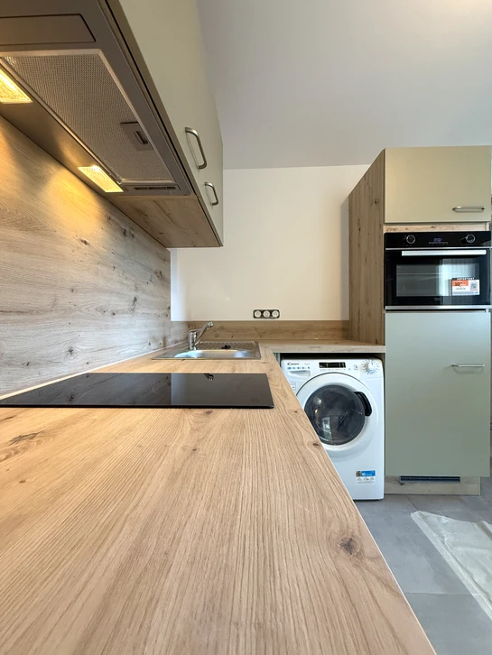 Cuisine moderne en mezzanine, façades laquées crème mat, poignées laiton brossé, plan de travail marbre blanc veiné