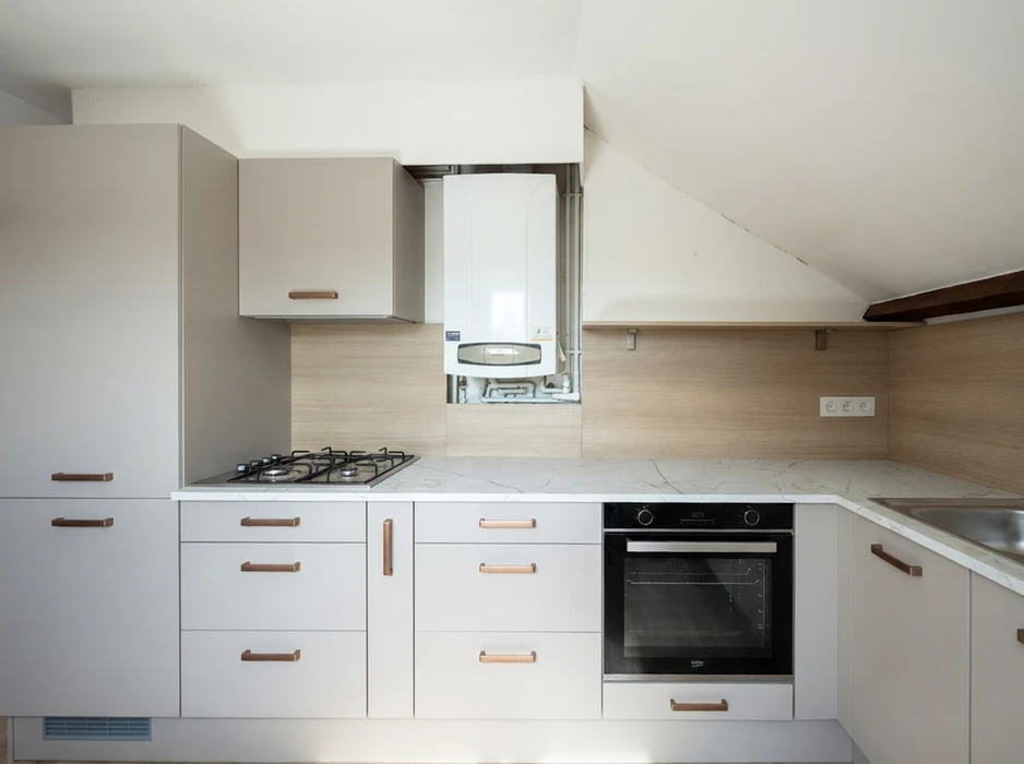 Cuisine en U moderne dans un appartement sous combles, lumière naturelle par fenêtre de toit Velux