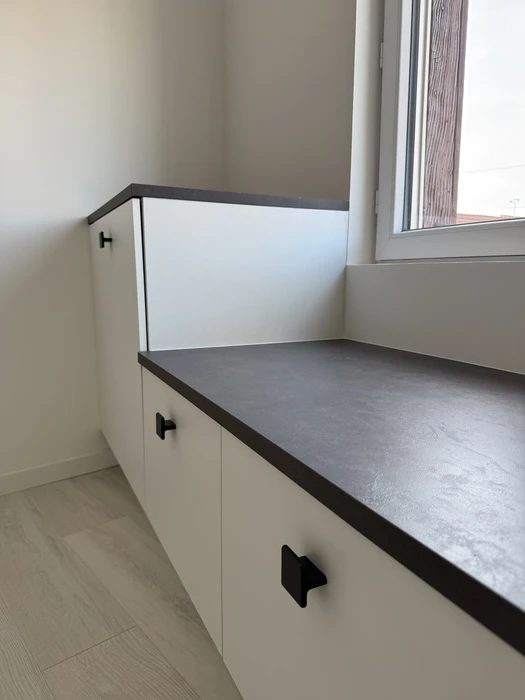 Meuble bas sur mesure blanc mat, plan de travail en stratifié effet béton gris anthracite, poignées carrées noires style industriel